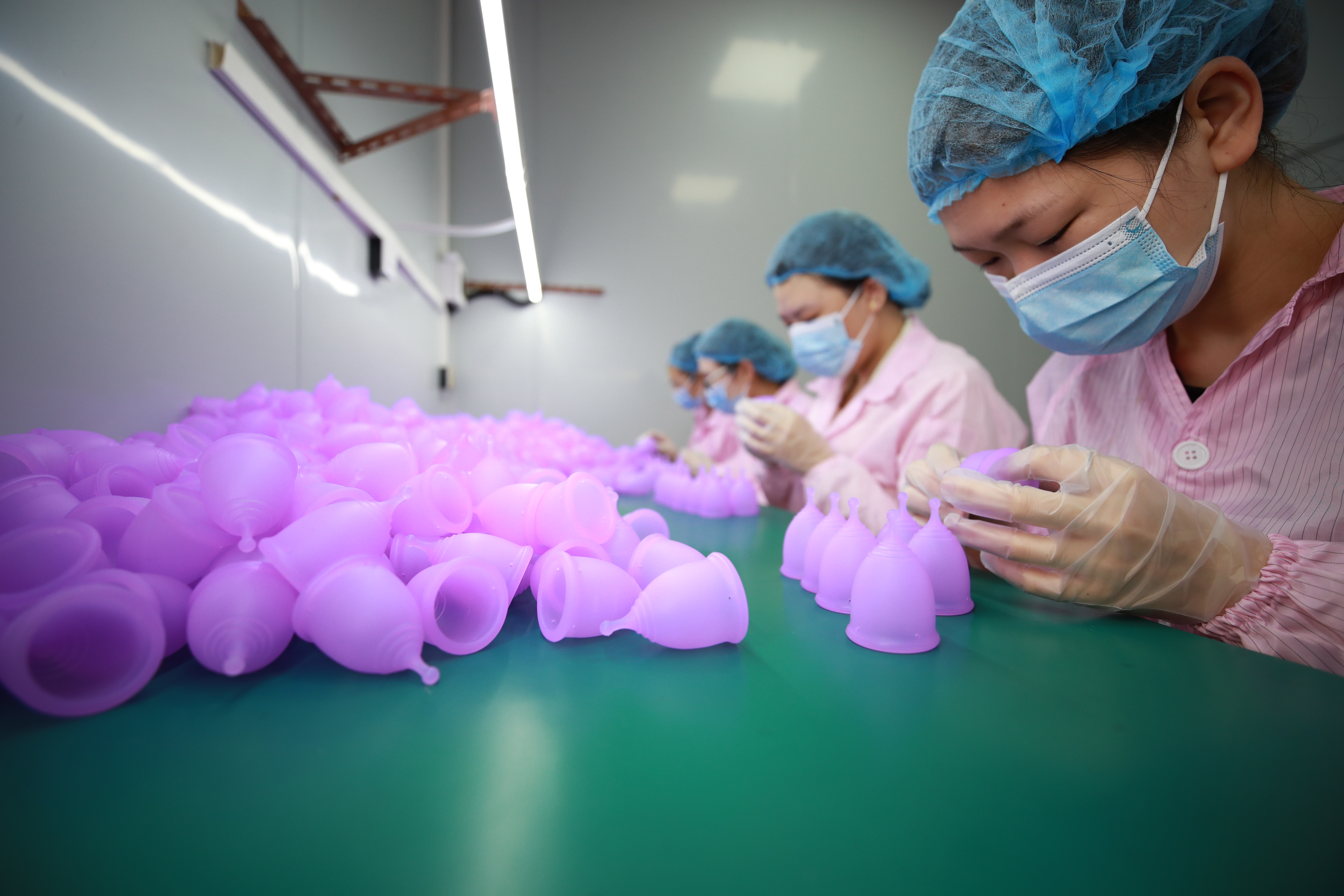 Sterile production protocol handling silicone menstrual cups on clean bench with gloved preparation
